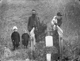 The Harvey Andrews family posed at the grave of son Willie Andrews, Custer County, New Helena vicinity, 1887; Standing at the graveside from left to right: Mary Andrews, Charles Henry Andrews, Harvey Andrews, Jennie Andrews holding daughter Lillian Andrew