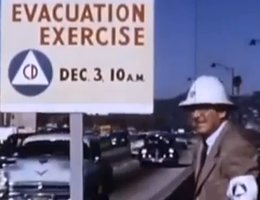 Man directing traffic in an evacuation drill from the 1964 film, "Let’s Face It"; Protesters were upset about the Civil Defense evacuation drills that they felt were designed to give people a false sense that they could survive a nuclear explosion