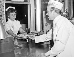 Eddy Gold handing a tray to a car hop at Ken Eddy’s Restaurant, 1953