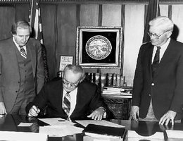 Nebraska Farmers Union President Neil Oxton (right) is pictured with Governor Charles Thone (seated) and Secretary of State Alan Beerman at the official signing ceremony of Initiative 300 in 1982