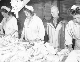 Women supervised by military personnel in meatpacking plant in World War II