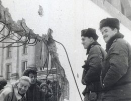 West Germans peer at East German border guards through a hole in the wall, January 5, 1990