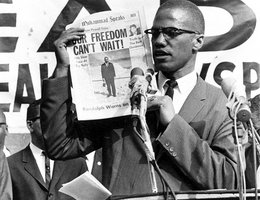 Malcolm X Holding a Copy of the Official NOI Newspaper