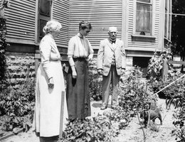In Grand Island, Nebraska, Edith Abbott (center) looking at a cat in the garden with parents Othman A. Abbott and Elizabeth Griffin Abbott